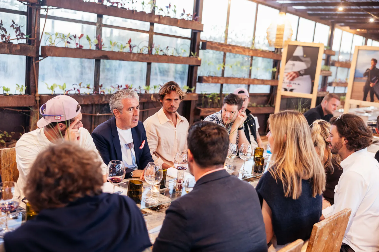 Guests sharing dinner at a long table in the Rio do Prado greenhouse.