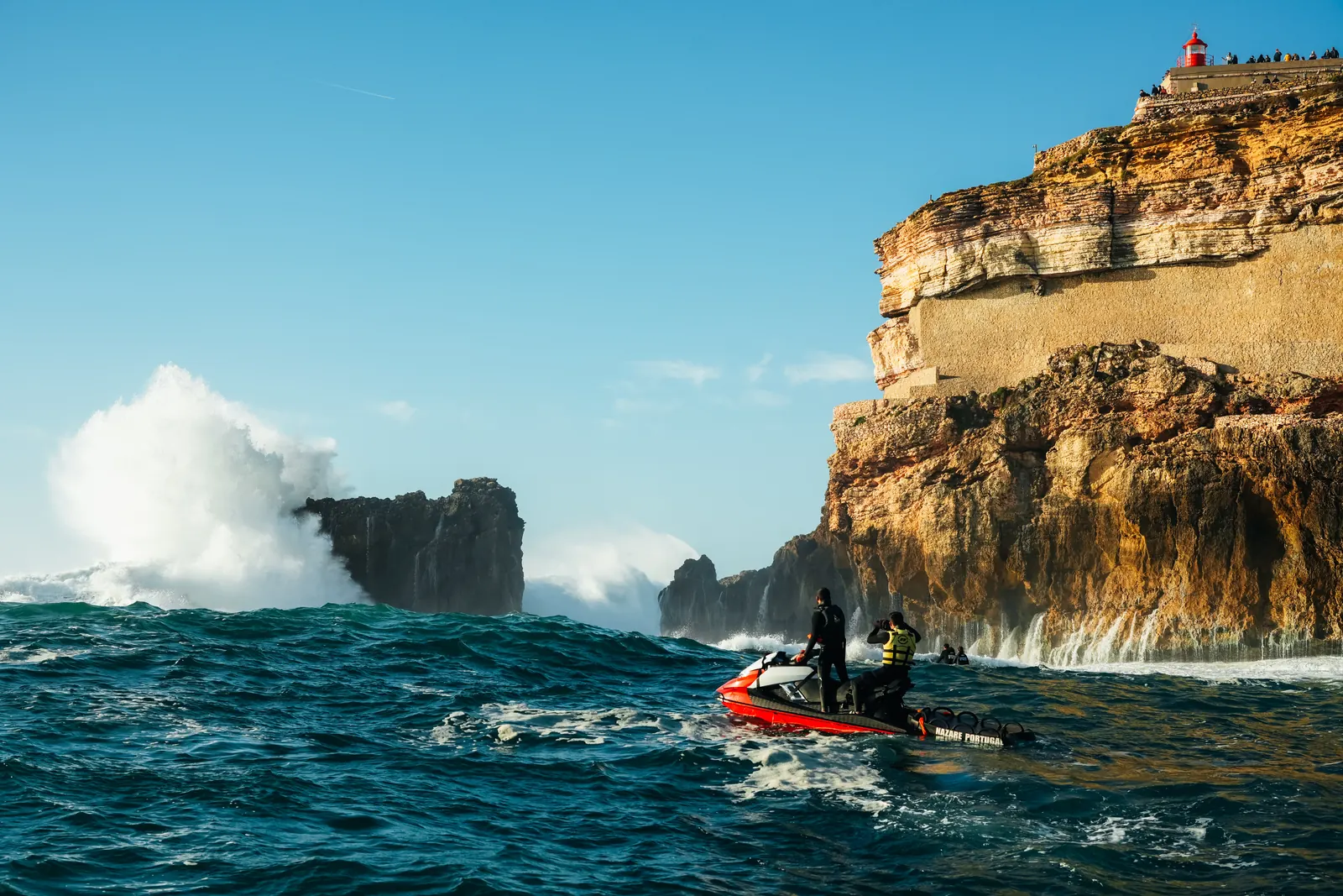 A Nazaré jet ski below the lighthouse cliffs.